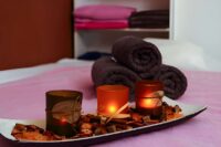 Massage studio St Petersburg spa setup with lit candles, rolled towels, and soothing botanicals for relaxation