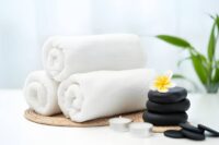 Wellness center St Petersburg FL spa arrangement with rolled towels, black stones, plumeria flower, and candles