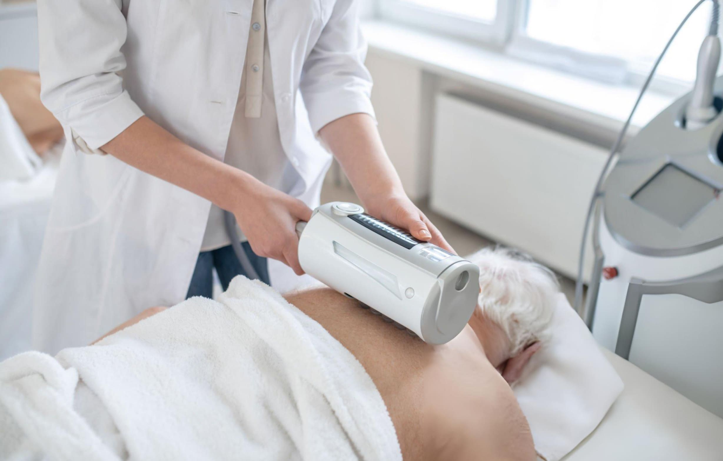 Softwave tissue regeneration technology therapy performed by healthcare professional using handheld device on elderly patient in clinic