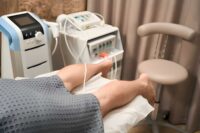 Neuromuscular therapy massage St Petersburg FL patient receiving leg treatment with electrodes and medical devices.