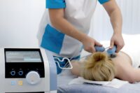Medical professional utilizing Softwave Tissue Regeneration Technology with a handheld applicator on a patient's back.