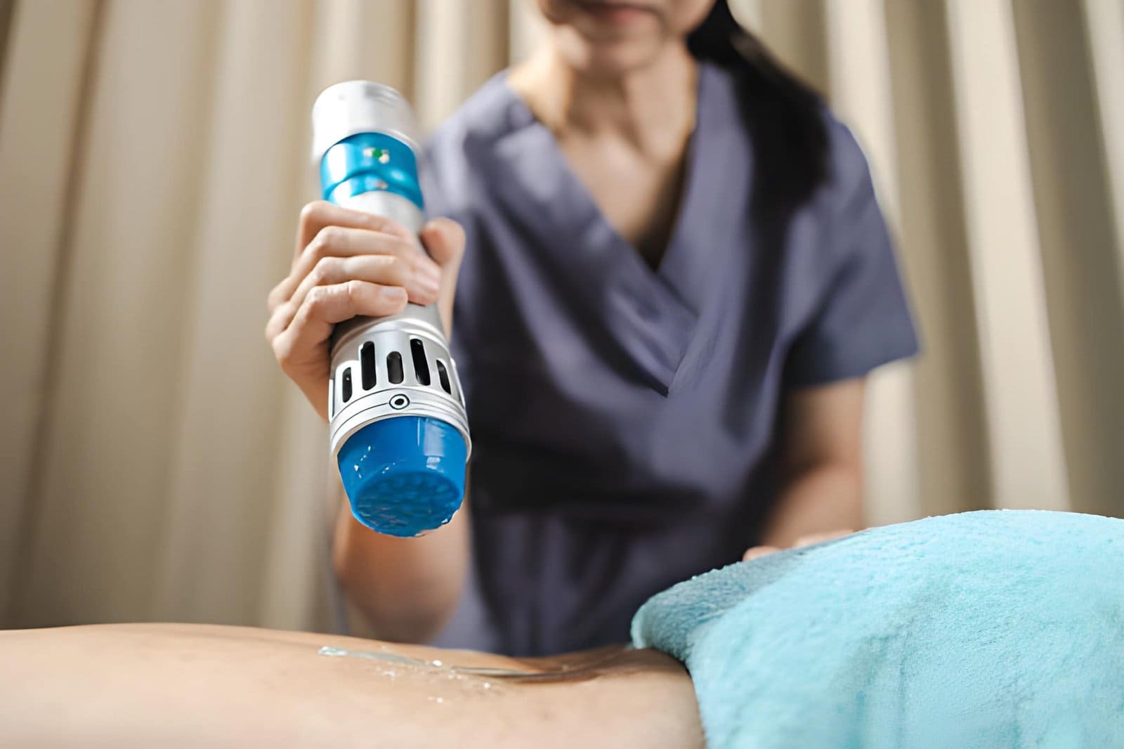 Softwave tissue regeneration technologies handheld device applied to patient’s skin with gel in clinical setting.