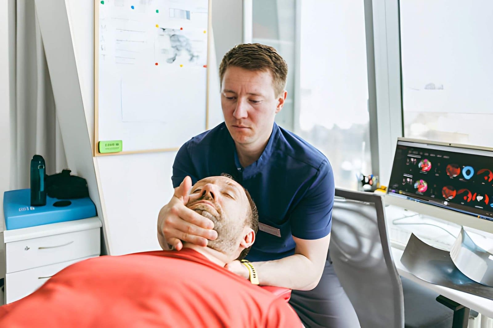 St Petersburg chiropractor performing neck adjustment on patient in clinical office with medical imaging in background.