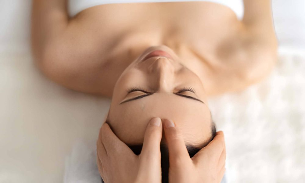 Holistic wellness center near me—person receiving head massage for relaxation and stress relief.