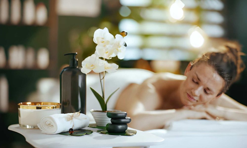 Massage studio St Petersburg serene setup with orchid, massage stones, candle, and client relaxation on massage table
