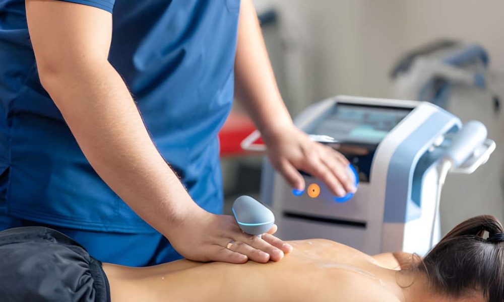 Softwave tissue regeneration technologies device applied to patient’s back in clinical setting.