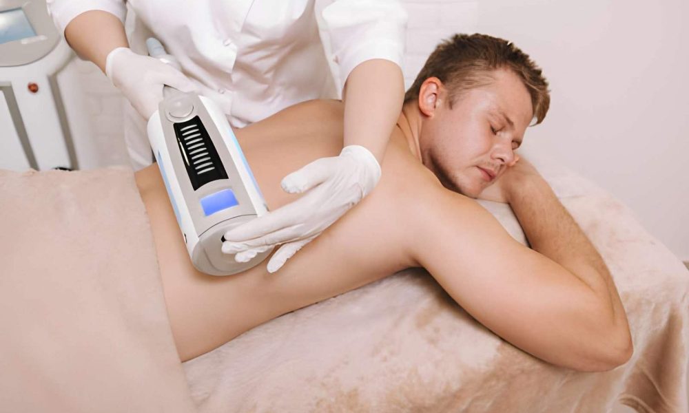 Softwave tissue regeneration technologies handheld device with digital display applied to patient back during therapy session